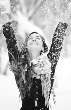 a woman is throwing snow in the air