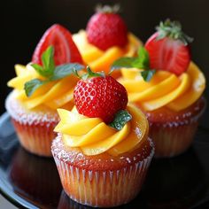 some cupcakes with fruit on top of them sitting on a black platter