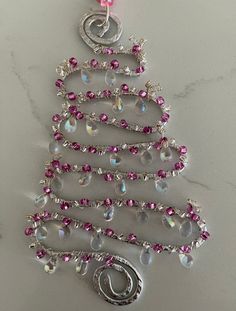 a christmas tree ornament with pink beads and swarongs on it