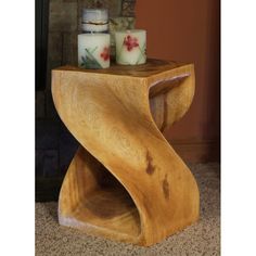 a wooden table with two candles on it and a candle holder next to it in front of a fireplace