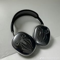 two black spiderman headphones sitting on top of a white table next to each other