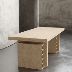 a wooden table sitting on top of a cement floor next to a white wall and concrete pillars