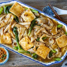 tofu and vegetable stir fry in a blue and white dish with chopsticks on the side