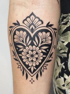 a black and white heart tattoo on the right arm, with flowers in the center