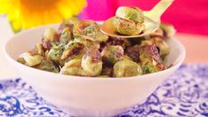 a white bowl filled with brussel sprouts on top of a blue and white table cloth