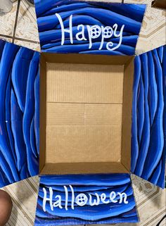 a cardboard box with blue streamers and the words happy halloween written on it