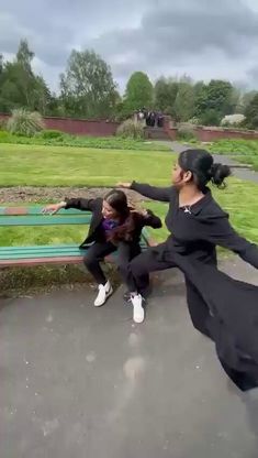 two women are sitting on a bench and one is holding her arms out in the air