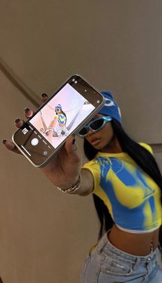 a woman taking a selfie with her cell phone while wearing a yellow and blue shirt