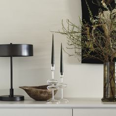 a white table topped with vases filled with flowers next to a lamp and painting