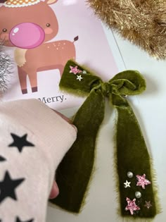 a green bow with pink stars on it next to a christmas card