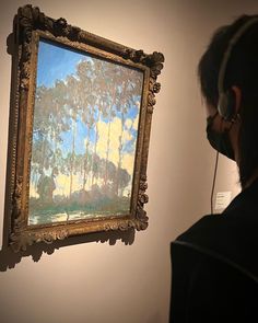 a person wearing headphones looking at a painting