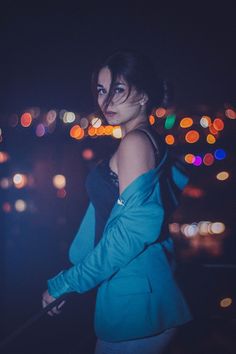 a woman standing in front of a city at night