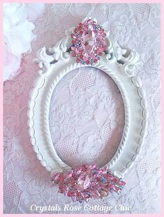 an ornate white frame with pink flowers and lace on the edge is featured in this photo