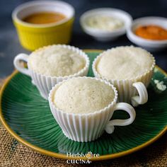 three cupcakes sitting on a green plate with saucers in front of them