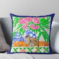 a cat sitting on top of a couch next to flowers and oranges throw pillow