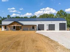 a large metal building sitting in the middle of a dirt field with two garages