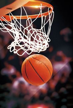 a basketball is going through the net in front of an audience