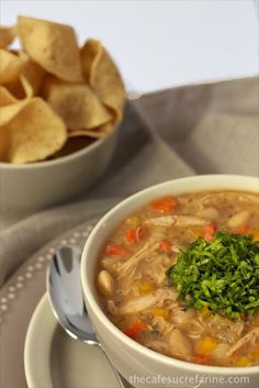 a white bowl filled with soup next to some chips