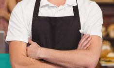 a man with his arms crossed wearing an apron