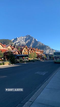 an empty street in front of some mountains with houses on each side and the words banff, alberita written below