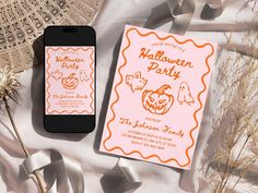 an orange and white halloween party card next to a cell phone