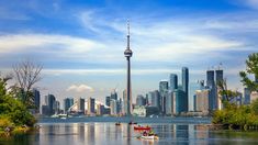 two small boats in the water near a large city with tall buildings on either side