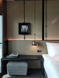 a room with a bed, table and lamp on the wall next to it in front of a window