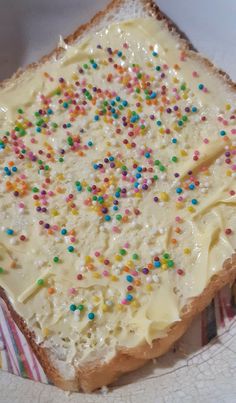 a piece of bread with white frosting and sprinkles