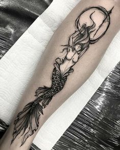 a black and white photo of a mermaid tattoo on the right arm with a half moon above it