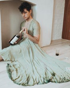 a man sitting on the floor holding a bottle of wine