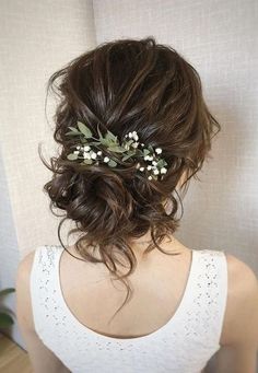 the back of a woman's head wearing a white top with flowers in her hair