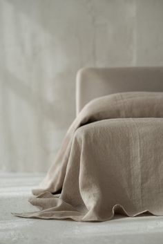 an unmade bed with linens on it and a white wall in the background