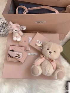 a teddy bear sitting on top of a table next to a pink bag and other items