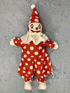 a red and white polka dot clown doll laying on the ground with its eyes closed