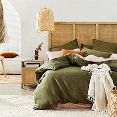 the bed is made with green linens and pillows