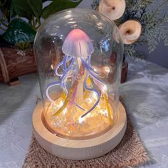 an illuminated jellyfish under a glass dome on a table