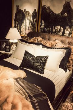 a bed with pillows and blankets in front of two horses on the wall behind it