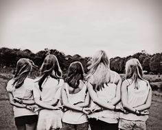 a group of women standing next to each other on top of a grass covered field