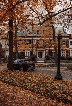 a black car parked on the side of a road in front of a large house