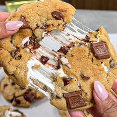 a person holding a giant cookie with ice cream and chocolate chips on it while eating