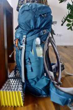 a blue backpack sitting on top of a hard wood floor next to a yellow object