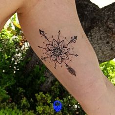 a woman's arm with an arrow and flower tattoo on the left side of her body