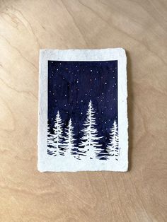 a piece of paper that has some trees on it and stars in the night sky