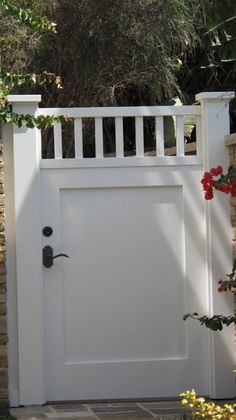 a white gate with red flowers growing on it