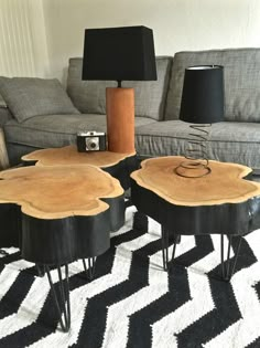 two wooden tables sitting on top of a black and white rug next to a couch