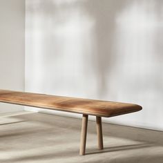 a wooden bench sitting on top of a floor next to a white wall in an empty room