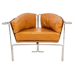 a tan leather chair with metal frame and two pillows on it's backrest