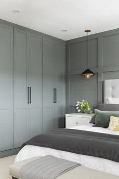 a bedroom with grey walls and white bedding, gray headboard, green pillows, yellow throw pillow