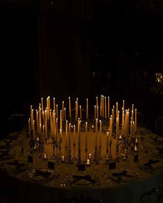 a table topped with lots of lit candles in the middle of it's center