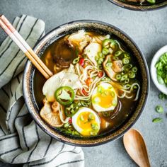 two bowls filled with soup and vegetables next to chopsticks on a table top